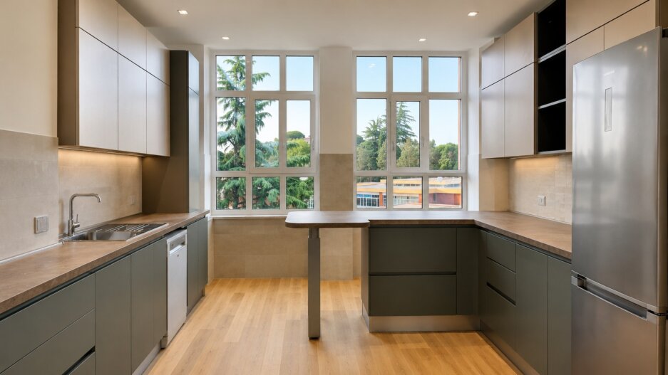 Cucina su misura realizzata a Roma con basi verde salvia, pensili chiari, piano effetto legno e penisola centrale.