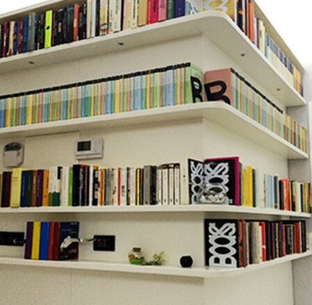 Libreria bianca con mensole curve che seguono l’angolo della parete